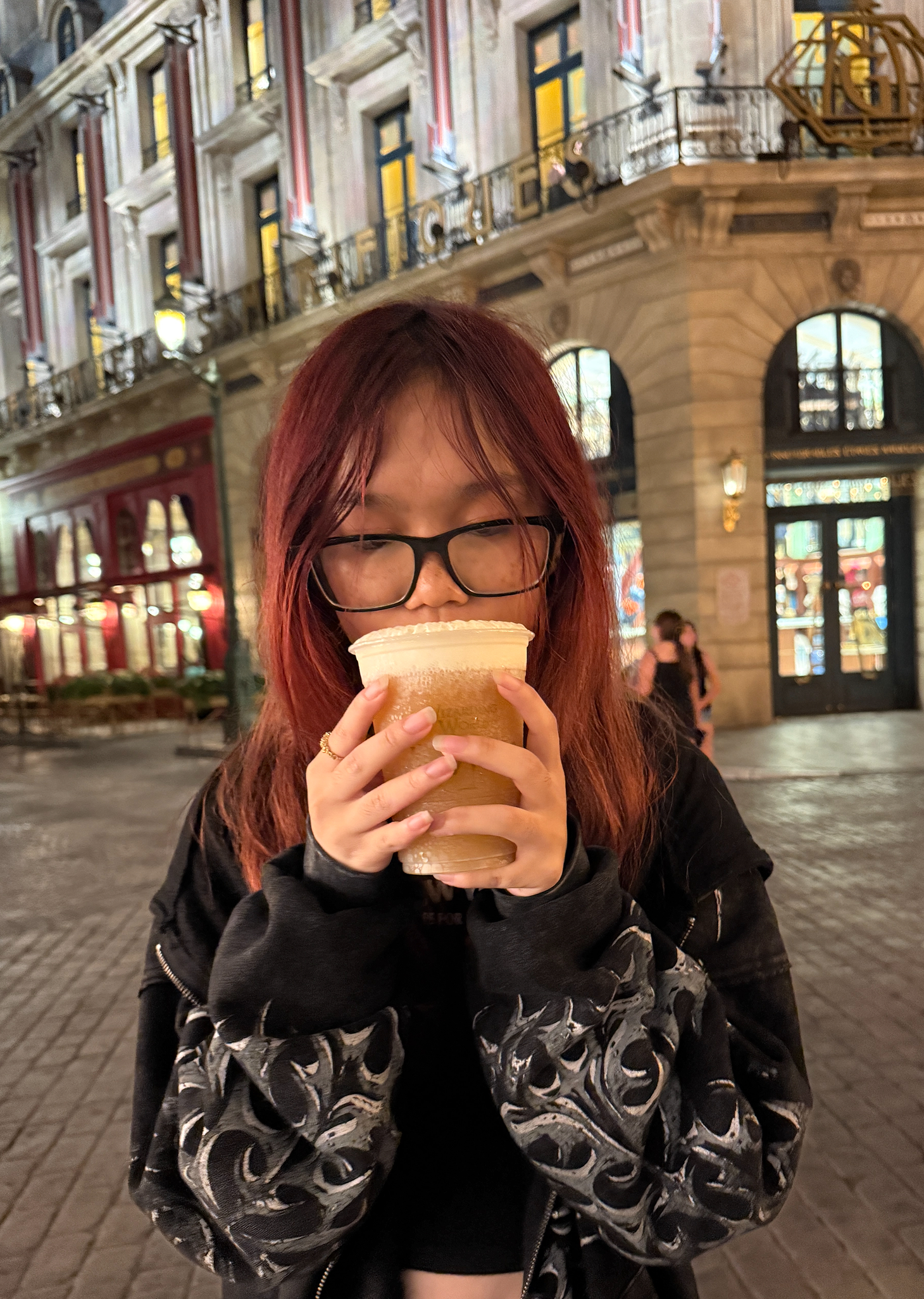 Tina Le holding a butterbeer at Universal Studios' Diagon Alley at night