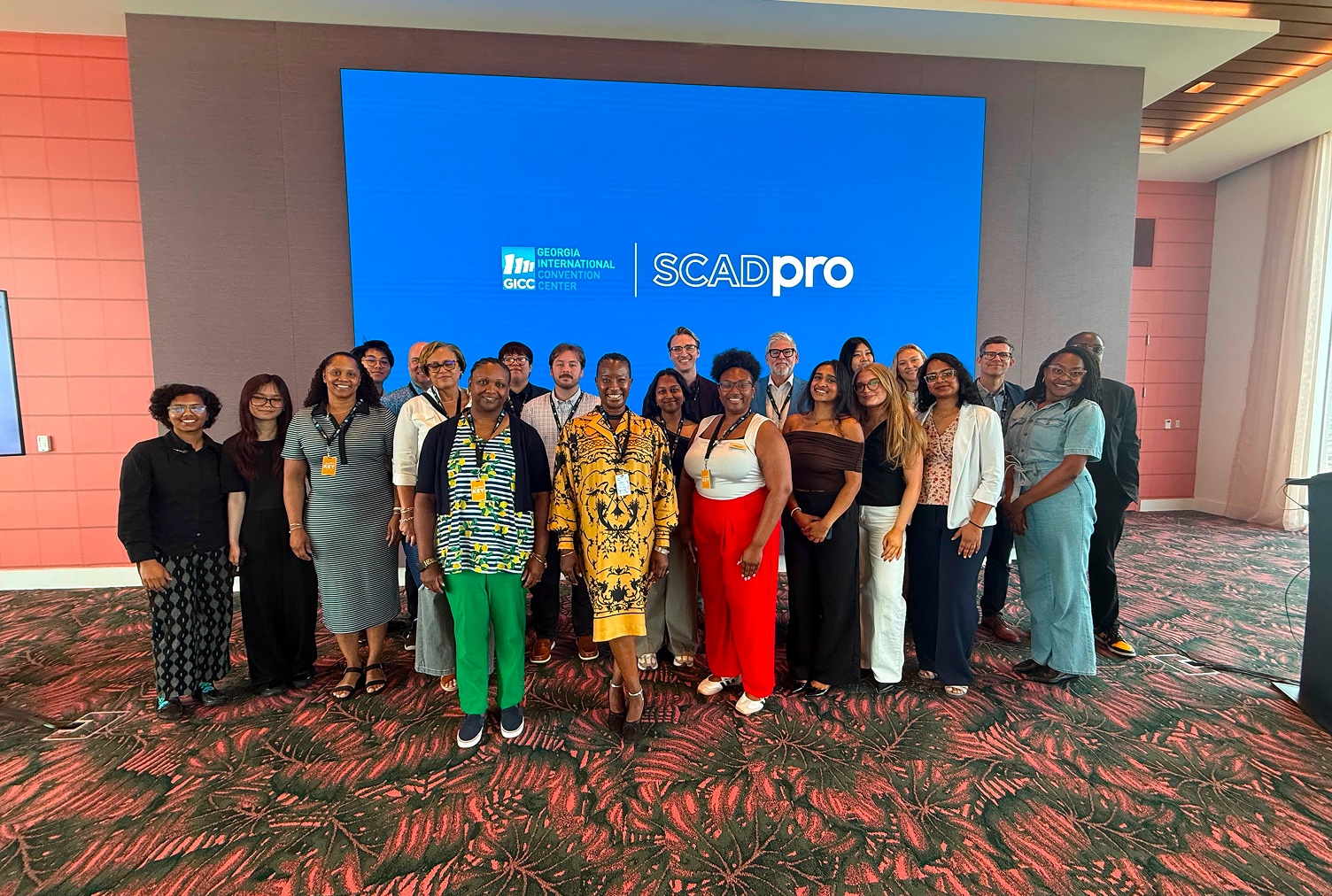 Group photo in front of a screen reading Georgia International Convention Center and SCADpro