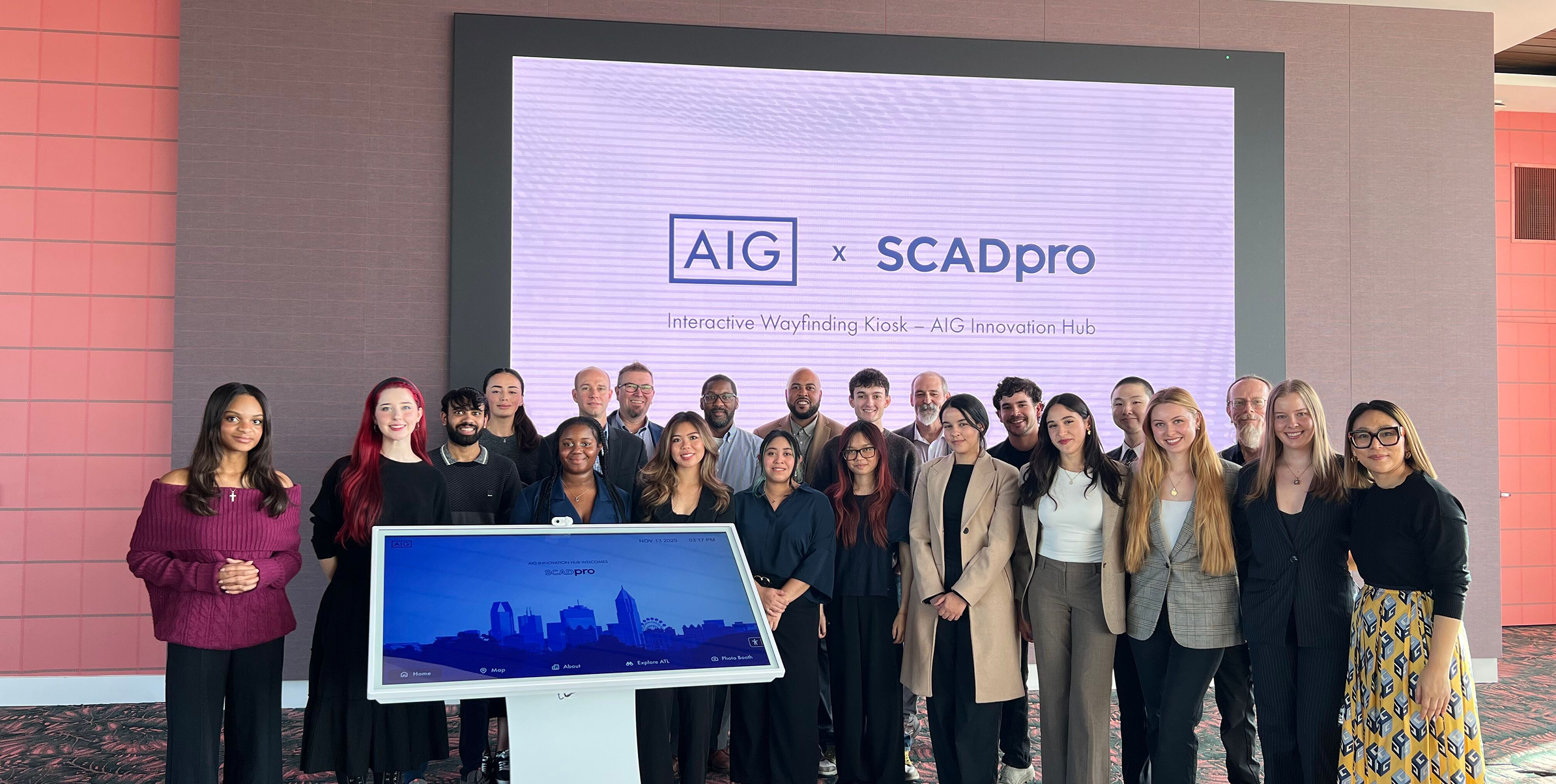 The AIG x SCADpro team posing with the kiosk prototype in front of an AIG x SCADpro welcome screen